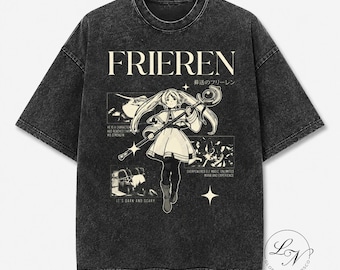 May include: A charcoal grey acid-wash t-shirt featuring a graphic of the character Frieren holding a staff. The design includes the text "FRIEREN" in a large serif font, Japanese characters, and smaller panels with text including "HE IS A CHARACTER" and "IT'S DARK AND SCARY."