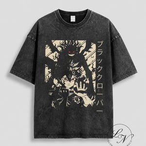 Puede incluir: Una camiseta gris carbón con efecto lavado al ácido que presenta un estampado gráfico de un personaje de anime con ojos rojos y una figura de sombra oscura detrás. El diseño incluye texto en japonés y un pequeño logo abajo a la derecha.