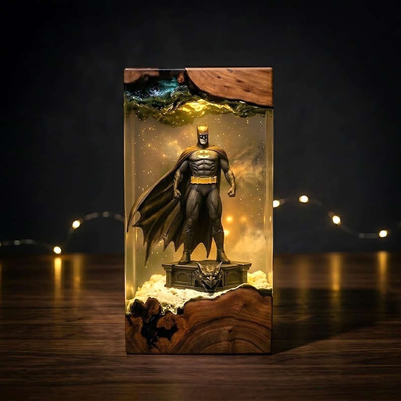 Puede incluir: Una l&aacute;mpara rectangular de resina y madera con una figura de Batman sobre una base de g&aacute;rgola. El cuerpo de resina transparente contiene un efecto de luz c&aacute;lida, mientras que las secciones superior e inferior est&aacute;n hechas de madera natural.
