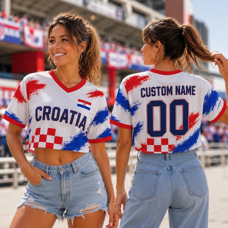 May include: A white V-neck crop top featuring red and blue brushstroke patterns, a red and white checkered design, and the text CROATIA on the front. The back displays the text CUSTOM NAME above the number 00 in dark blue, with matching patterns.