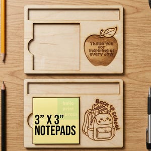 Può includere: Due organizer da scrivania rettangolari in legno chiaro con scomparti per blocchetti da 7,62 cm per 7,62 cm. L'organizer superiore presenta una mela incisa con il testo Thank you for inspiring us every day e quello inferiore uno zaino.