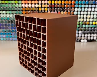 May include: A brown rectangular storage organizer featuring a grid of numerous square compartments. The unit has a solid top and side panel, with an open front face displaying a structured matrix of individual cubbies for holding small items.