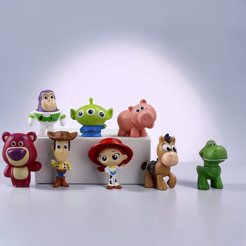 May include: A collection of eight small plastic character figurines including a purple and white space ranger, a green three-eyed alien, a pink pig, a purple bear, a cowboy, a cowgirl with a red hat, a brown horse, and a green dinosaur.