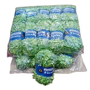 Puede incluir: Un paquete de ovillos de lana de color verde claro con textura envueltos en plástico transparente. Cada ovillo tiene una etiqueta de papel azul con el texto Luz Color Fiesta impreso en blanco. El hilo tiene un aspecto rizado y en bucle.