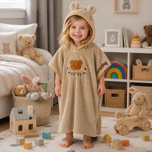 Peut inclure: Un poncho de bain à capuche beige orné d'une broderie en forme de tête d'ours sur la poitrine, d'oreilles d'ours sur la capuche et du nom Abernethy brodé sur le côté. Le tissu doux et pelucheux offre une couverture complète et une grande aisance.