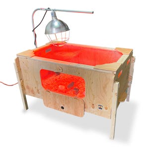 May include: A wooden brooder with a red heat lamp and a red mesh floor. The brooder has a small window to view the chicks inside.