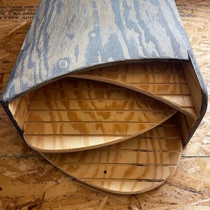 May include: A wooden tiered storage shelf with a dark gray stain. The shelf has three tiers with rounded edges and is open on the front. The shelf is made of plywood and has a natural wood grain.
