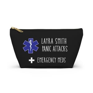 Könnte beinhalten: Eine schwarze Reißverschlusstasche mit einem blauen medizinischen Stern des Lebens, dem weißen Text Layra Smith Panic Attacks und dem weißen Text Emergency Meds mit einem weißen Kreuzsymbol. Die Tasche hat einen goldenen Reißverschluss.