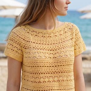 Pode incluir: Um top de croch&ecirc; amarelo de manga curta com decote redondo e um intrincado padr&atilde;o rendado repetitivo em toda a pe&ccedil;a. O item &eacute; constru&iacute;do com uma textura de fio delicada, exibindo fileiras horizontais de diversos pontos de croch&ecirc;.
