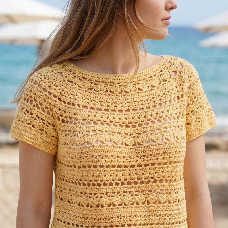 Pode incluir: Um top de croch&ecirc; amarelo de manga curta com decote redondo e um intrincado padr&atilde;o rendado repetitivo em toda a pe&ccedil;a. O item &eacute; constru&iacute;do com uma textura de fio delicada, exibindo fileiras horizontais de diversos pontos de croch&ecirc;.