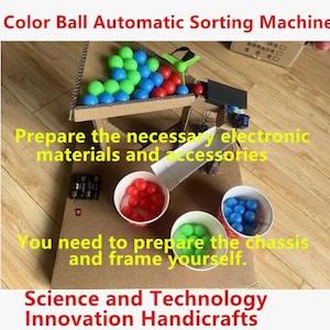 Puede incluir: Un proyecto de máquina clasificadora automática de bolas de colores con marco de cartón, embudo, canaleta blanca y tres vasos blancos con bolas de plástico rojas, azules y verdes. Componentes electrónicos visibles en la base.