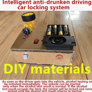 Könnte beinhalten: Ein intelligentes Anti-Trunkenheits-Autoverriegelungssystem als DIY-Projekt mit einer Kartonbasis, einem gelben Motor mit schwarzem Rad, vier AA-Batterien, einem schwarzen Lautsprecher, einem roten Netzschalter und zwei Sensoren.