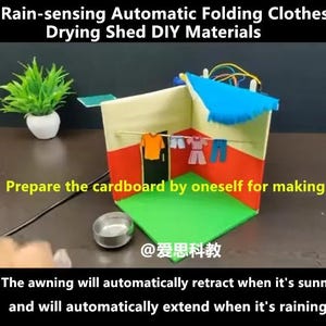 May include: A DIY model of a rain-sensing automatic folding clothes drying shed featuring a cardboard structure with red and yellow walls, a green floor, and a blue retractable awning. Miniature clothing hangs on a line inside the structure.