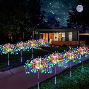 Op de afbeelding: Een reeks tuinverlichting op staken met veelkleurige LED-displays in de vorm van vuurwerk. Elke lamp bestaat uit dunne, flexibele draadtakken die naar buiten stralen, bekroond met kleine gloeiende rode, blauwe, groene en gele lampjes.
