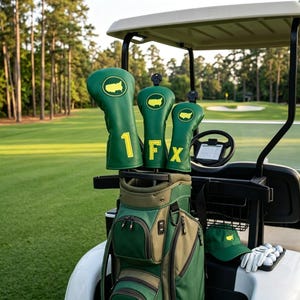Può includere: Tre coperture verdi per mazze da golf con contorni ricamati in giallo degli Stati Uniti e le lettere 1, F e X. Le coperture sono in una sacca da golf verde e beige con diverse tasche con cerniera, insieme a un berretto verde e palline da golf.