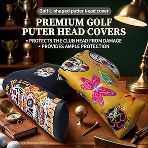 May include: Two L-shaped golf putter head covers, one black and one mustard yellow, featuring embroidered sugar skull, butterfly, and rose designs. The black cover displays text reading 'PATH TO LIFE' and 'ARLON G'.