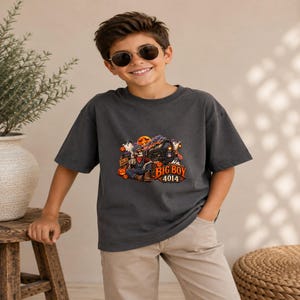May include: A charcoal gray short-sleeve t-shirt featuring a graphic print of a skeleton conductor sitting in front of a steam locomotive. The design includes orange pumpkins, white ghosts, and the text "BIG BOY 4014" in a bold orange font.