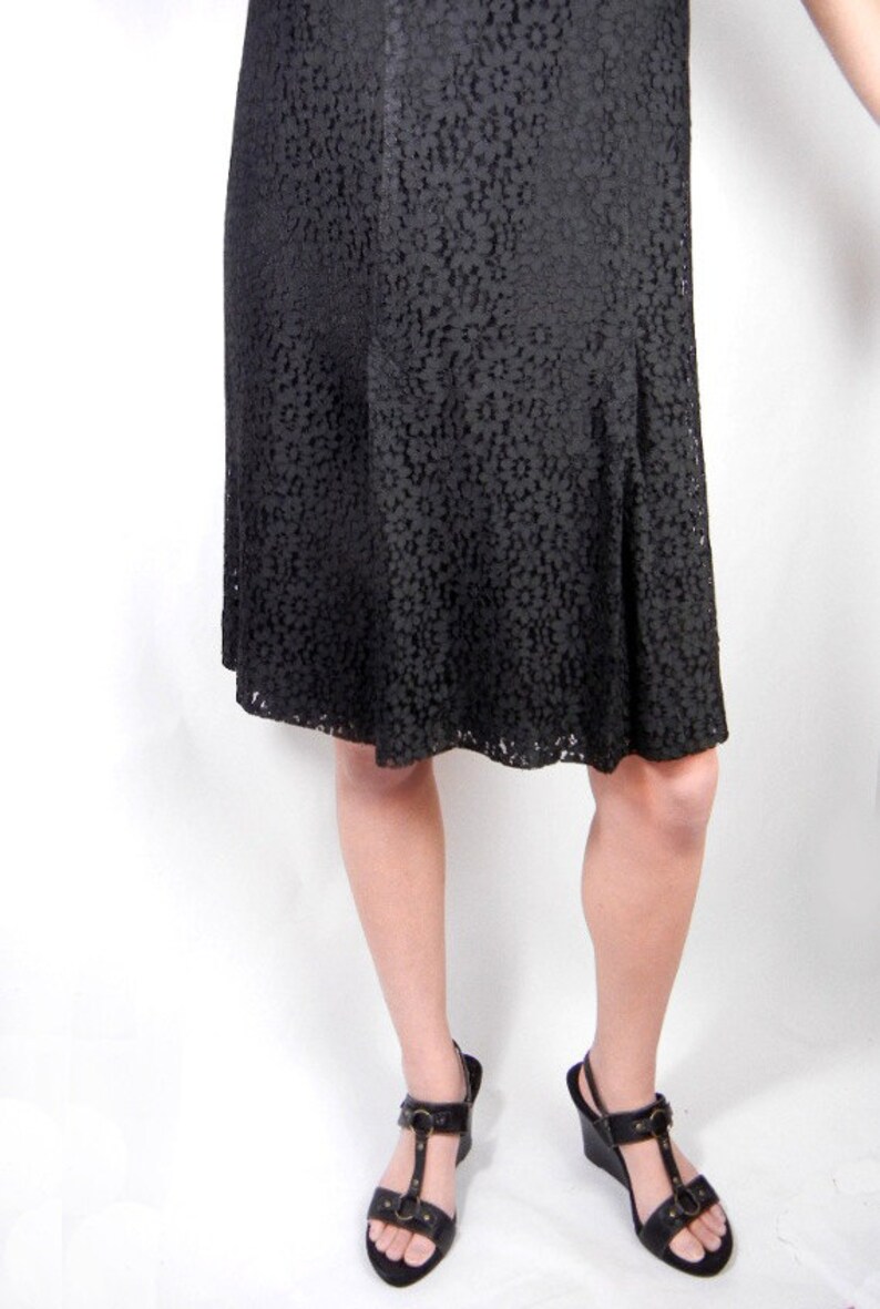 May include: A black lace dress with a flared skirt and a pair of black heeled sandals with buckles.