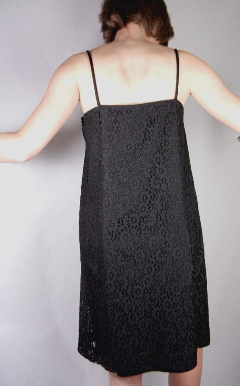 May include: A black lace dress with thin straps. The dress has a fitted bodice and a slightly flared skirt.
