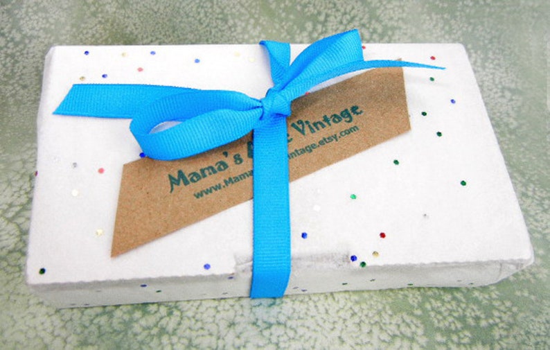 May include: A white gift box with a blue ribbon and a brown tag that says "Mama's Vintage www.MamaVintage.etsy.com". The box is covered in small, colorful confetti.
