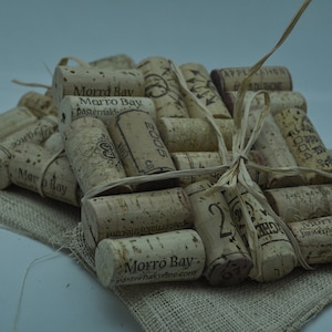 Puede incluir: Un montón de tapones de vino usados ​​atados con cuerda, algunos de los tapones tienen las palabras "Morro Bay" y "Pasternak" impresas en ellos.