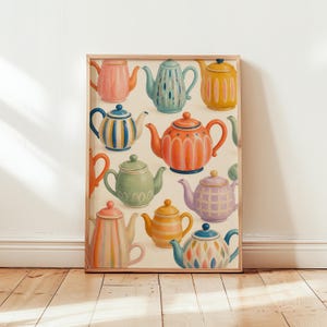 Peut inclure: Une impression d'art encadrée présentant une collection de onze théières colorées aux formes et motifs variés, incluant des rayures, des carreaux et des motifs de feuilles, dans des tons rose, bleu, jaune, orange, vert et violet sur fond crème.