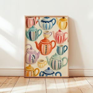 May include: A framed art print featuring a collection of colourful painted teapots and creamers in various patterns, including stripes, dots, and floral motifs, set against a cream background. The teapots are rendered in shades of blue, pink, orange, yellow, and purple.
