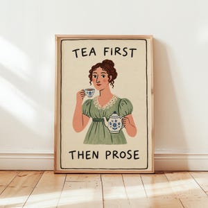 May include: A framed art print on a cream background featuring an illustration of a person with brown hair in a green dress holding a teacup and teapot. The text reads TEA FIRST at the top and THEN PROSE at the bottom in black capital letters.