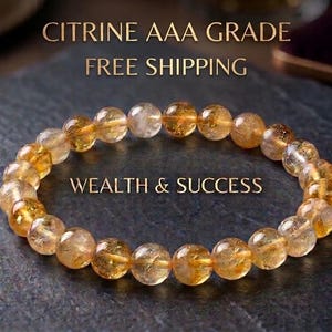 May include: A circular bracelet composed of translucent, golden-yellow citrine gemstone beads. The text CITRINE AAA GRADE and WEALTH & SUCCESS is visible. The beads are polished and spherical, displaying natural internal inclusions and variations.