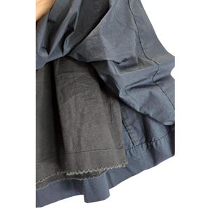 Puede incluir: Primer plano de una prenda azul oscuro con un dise&ntilde;o en capas. La capa exterior tiene una textura suave y ligeramente brillante, mientras que la capa interior es de un tono m&aacute;s oscuro con un borde festoneado. La tela parece ligera.