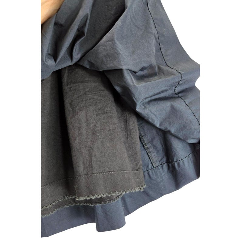 Puede incluir: Primer plano de una prenda azul oscuro con un dise&ntilde;o en capas. La capa exterior tiene una textura suave y ligeramente brillante, mientras que la capa interior es de un tono m&aacute;s oscuro con un borde festoneado. La tela parece ligera.