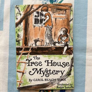 May include: A vintage hardcover book titled "The Tree House Mystery" by Carol Beach York, illustrated by Reisie Lonette. The cover shows an illustration of children near a treehouse, with a ladder and a window.