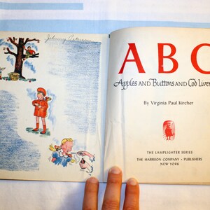 May include: A vintage children's book titled "ABC Apples and Buttons and Cod Liver Oil" by Virginia Paul Kircher. The cover features a red, white, and blue illustration of a child holding an apple.