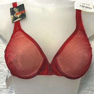May include: A bright red underwire bra featuring sheer mesh cups with a subtle shimmer, scalloped trim along the neckline, and adjustable shoulder straps. A product tag attached to the strap displays the text T/M Wire and Titanium Memory Wire.