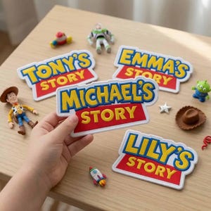 May include: Four embroidered fabric patches featuring the text 'Tony's Story', 'Emma's Story', 'Michael's Story', and 'Lily's Story' in yellow letters with blue outlines on a red background, surrounded by small plastic character figurines.