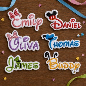 May include: Six embroidered name patches featuring Disney-inspired motifs. The names Emily, Daniel, Oliva, Thomas, James, and Buddy are stitched in various colours, including pink, red, purple, blue, green, and yellow, with character-themed accents.