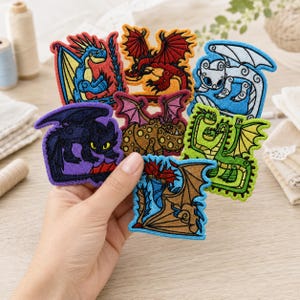 May include: A collection of seven embroidered fabric patches featuring various dragon designs in vibrant colors including blue, red, white, black, brown, and green. Each patch displays a unique dragon character with detailed stitching and outlines.
