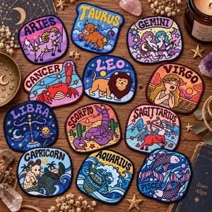 Puede incluir: Una colección de doce parches bordados con ilustraciones coloridas de los signos del zodiaco Aries, Tauro, Géminis, Cáncer, Leo, Virgo, Libra, Escorpio, Sagitario, Capricornio, Acuario y Piscis, cada uno con su nombre claramente impreso.