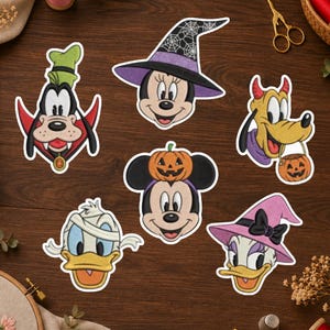 May include: A collection of six Disney character stickers featuring Goofy as a vampire, Minnie Mouse in a spiderweb witch hat, Pluto as a devil, Mickey Mouse with a pumpkin on his head, Donald Duck as a mummy, and Daisy Duck in a pink witch hat.