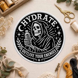 May include: A circular embroidered patch featuring a black background with white thread detailing. The design depicts a hooded skeleton holding a water bottle, surrounded by the text HYDRATE and OUTLIVE YOUR ENEMIES, accented by stars and leaves.