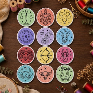 May include: Twelve circular embroidered patches featuring black line art of the zodiac signs. Each patch has a unique pastel background colour, including light green, peach, yellow, purple, lavender, blue, red, and pink, with white stitched borders.