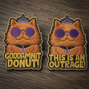 May include: Two embroidered patches featuring an orange cat wearing a purple crown, purple round sunglasses, and a black collar with a butterfly charm. The left patch reads GODDAMNIT DONUT! and the right patch reads THIS IS AN OUTRAGE!