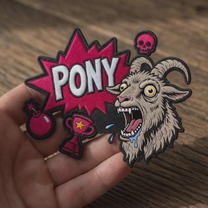 May include: An embroidered patch featuring a pink comic-style speech bubble with the white text PONY, a pink bomb, a pink trophy with a yellow star, a small pink skull, and a detailed illustration of a screaming goat with drool and horns.