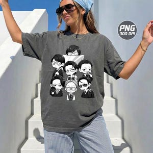 May include: A charcoal grey short-sleeve t-shirt featuring a graphic print of seven chibi-style characters in suits and glasses. The design is rendered in black and white, showcasing various expressions and poses. The shirt has a relaxed, loose fit.