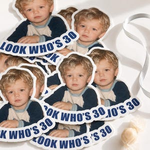 Può includere: Una collezione di adesivi fustellati con la fotografia di un bambino biondo che indossa una maglietta in stile baseball blu navy e crema. Il testo "LOOK WHO'S 30" è stampato in grassetto con lettere maiuscole blu in basso.
