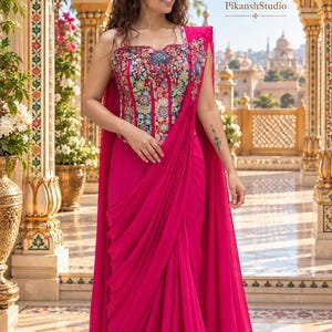 Op de afbeelding: Een levendige fuchsia sari met een gestructureerd korset-achtig lijfje met ingewikkeld veelkleurig bloemenborduurwerk en kralenwerk. Het kledingstuk bevat een vloeiende, geplooide rok en een gedrapeerde pallu, met de tekst PikanshStudio.