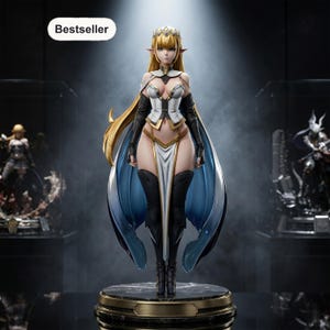 May include: A standing female elf figurine with long blonde hair, wearing a white and gold bodice, black arm sleeves, and a flowing blue cape. The character features pointed ears, a gold crown, and stands on a circular black marble base with text Bestseller.