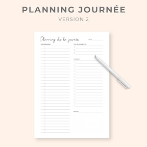 K&ouml;nnte beinhalten: Ein wei&szlig;er Tagesplaner mit dem Text "PLANNING JOURN&Eacute;E VERSION 2" oben. Der Planer enth&auml;lt Abschnitte f&uuml;r "PROGRAMME", "TOP 3 PRIORIT&Auml;TEN" und "A FAIRE". Ein wei&szlig;er Stift liegt auf der Seite.
