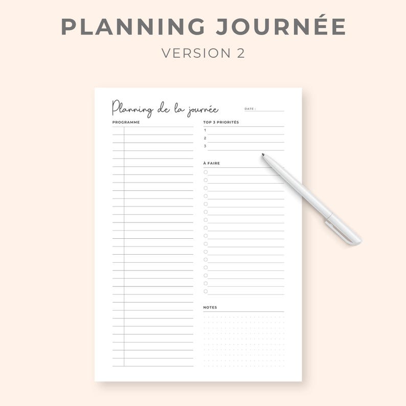 K&ouml;nnte beinhalten: Ein wei&szlig;er Tagesplaner mit dem Text "PLANNING JOURN&Eacute;E VERSION 2" oben. Der Planer enth&auml;lt Abschnitte f&uuml;r "PROGRAMME", "TOP 3 PRIORIT&Auml;TEN" und "A FAIRE". Ein wei&szlig;er Stift liegt auf der Seite.