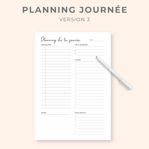 K&ouml;nnte beinhalten: Ein wei&szlig;er Papierplaner mit dem Text "PLANNING JOURN&Eacute;E VERSION 3" oben. Der Planer enth&auml;lt Abschnitte f&uuml;r die Tagesplanung, die wichtigsten Priorit&auml;ten, To-Do-Listen, Notizen und einen Abschnitt f&uuml;r morgen. Ein wei&szlig;er Stift liegt auf der Seite.